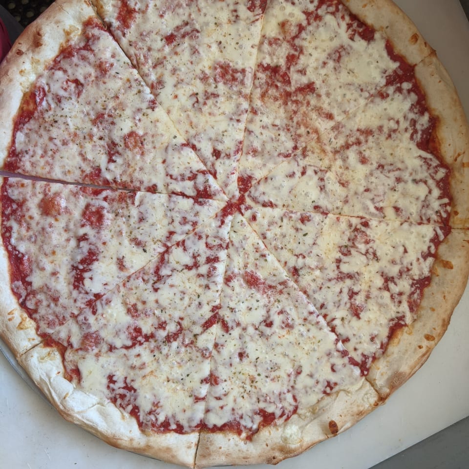 A freshly baked, sliced cheese pizza from The Deli & Pizza Shop, with a crispy crust.