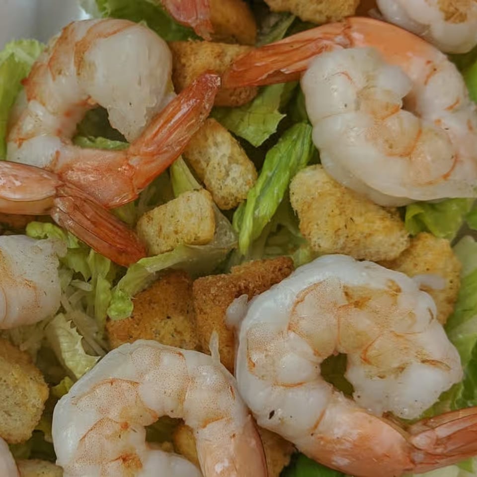 Close-up of a shrimp salad with lettuce and croutons from The Deli & Pizza Shop.